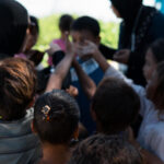 A bunch of kids extending their hand to ask for homeless winter survival kit